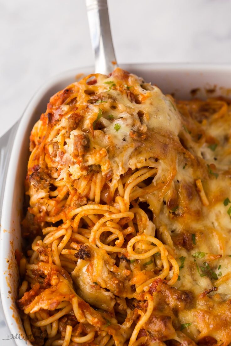 ladle scooping spaghetti out of casserole dish