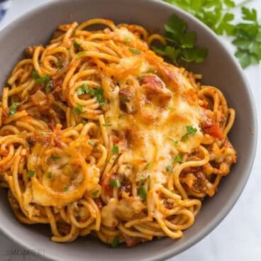 baked spaghetti in a grey bowl with parsley on top.