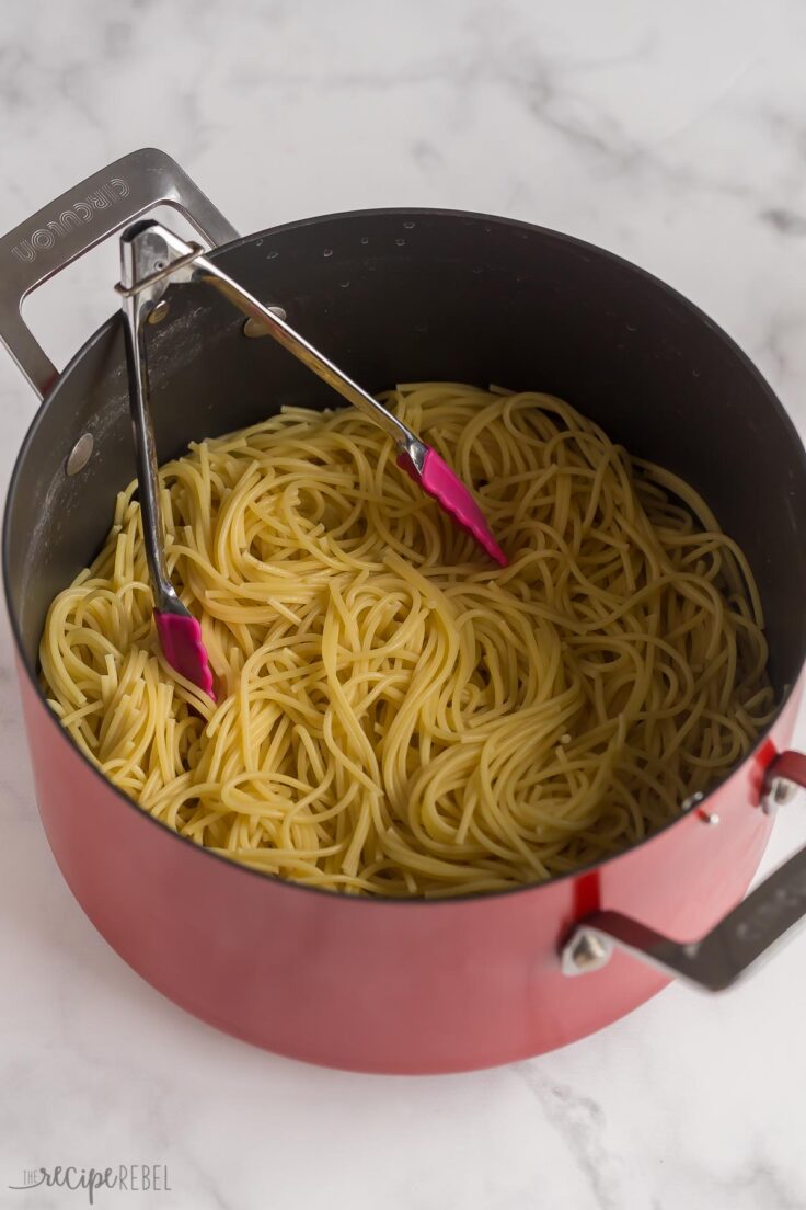 cooked spaghetti in large pot with tongs