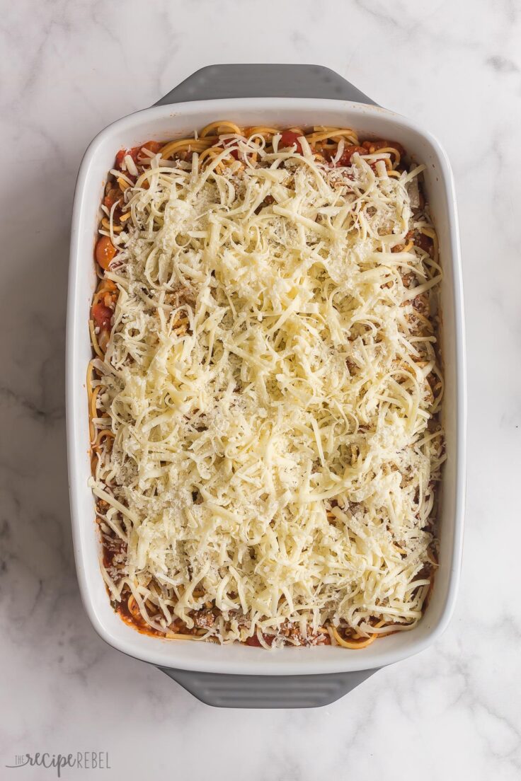 baked spaghetti in baking dish with cheese on top before baking