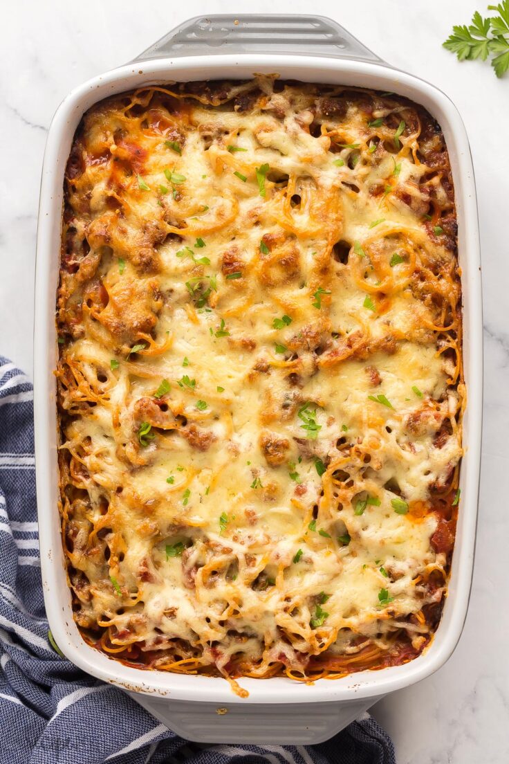 This easy Baked Spaghetti is made with a homemade Italian sausage spaghetti sauce, cooked spaghetti and loads of cheese! Make ahead and freezer friendly! #pasta #spaghetti #dinner overhead image of baked spaghetti on white background