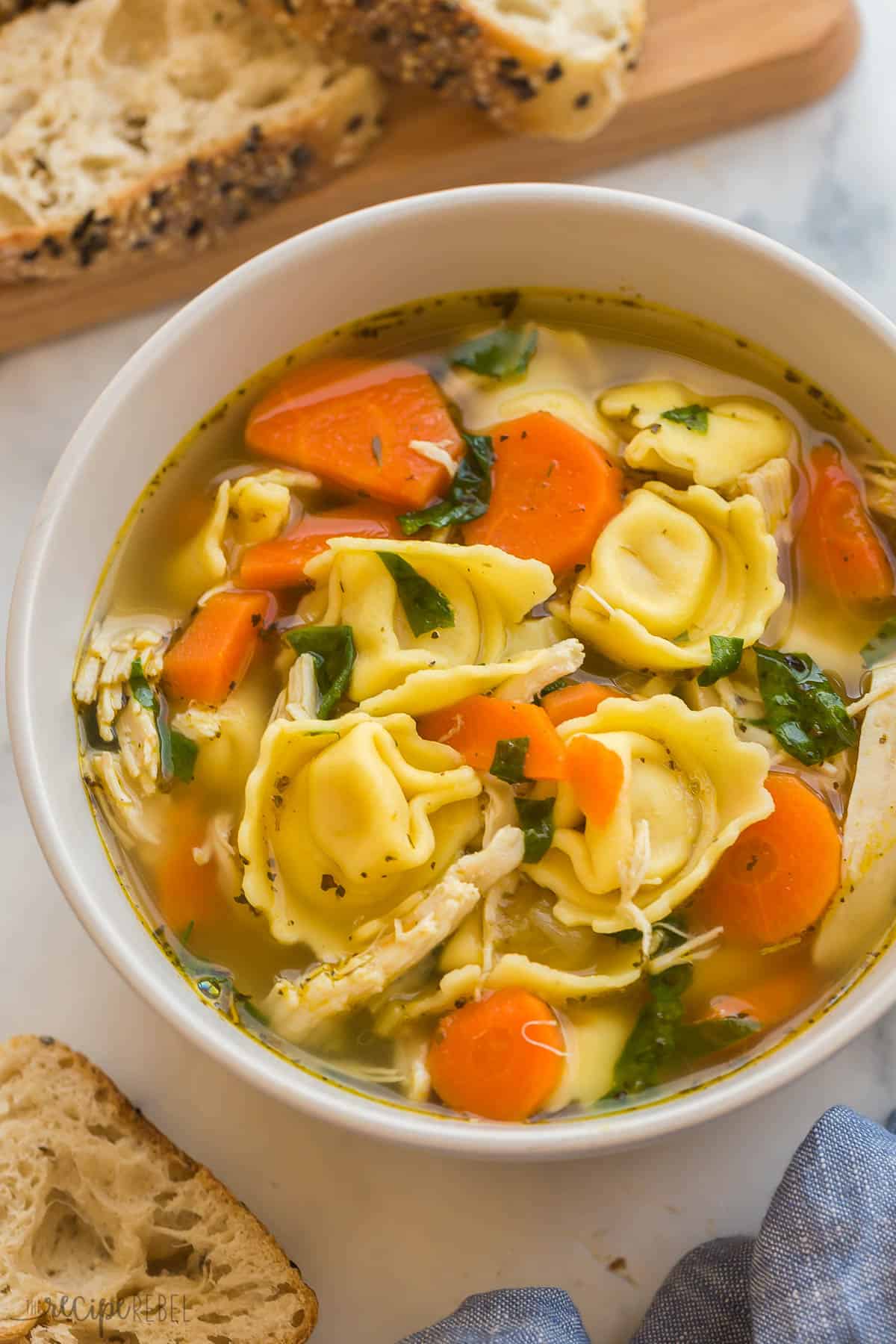close up image of chicken tortellini soup in beige bowl