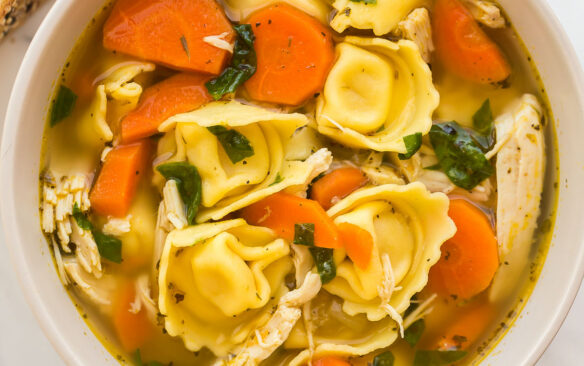 square overhead image of a bowl of chicken tortellini soup