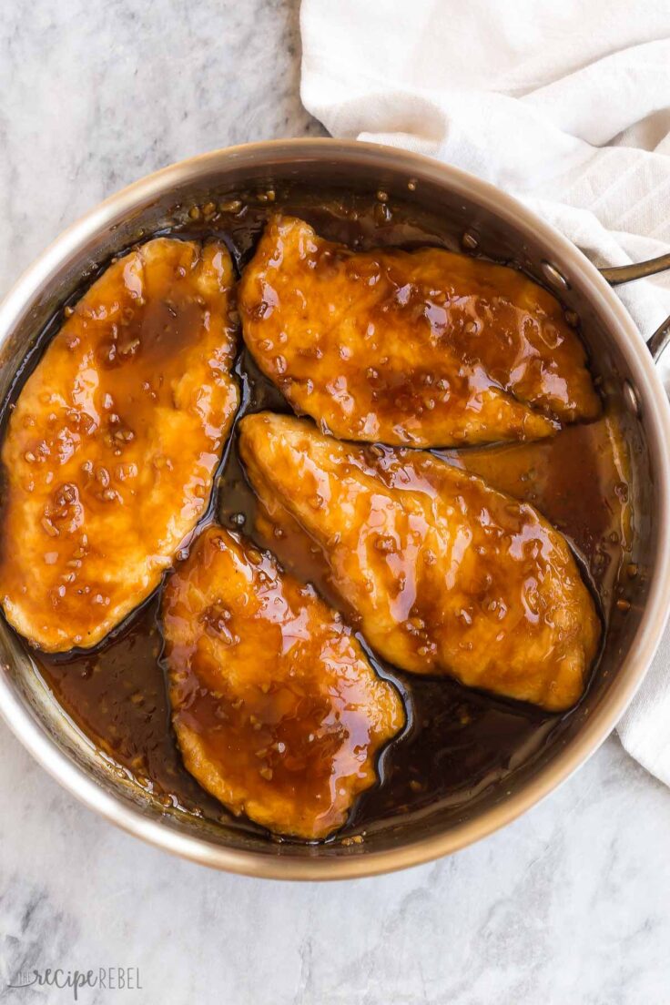 This Honey Garlic Chicken is the perfect weeknight dinner! It's a 25-minute recipe made up of tender chicken cooked in a sweet, salty, gooey, sticky, and flavorful honey garlic sauce. #chicken #dinner #recipes | easy chicken recipe | chicken breast | easy dinner ideas | skillet dinner four chicken breasts in a skillet with honey garlic sauce