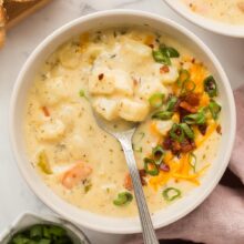 square image of potato soup in bowl with spoon stuck in
