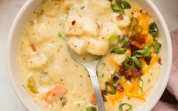 square image of potato soup in bowl with spoon stuck in