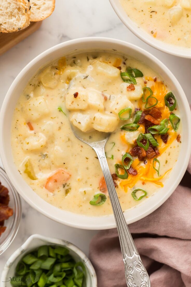 close up image of potato soup in bowl with spoon stuck in