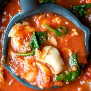 close up image of slow cooker tortellini soup in ladle