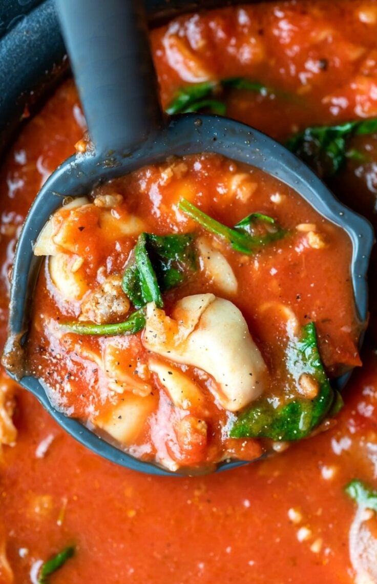 close up image of slow cooker tortellini soup in ladle