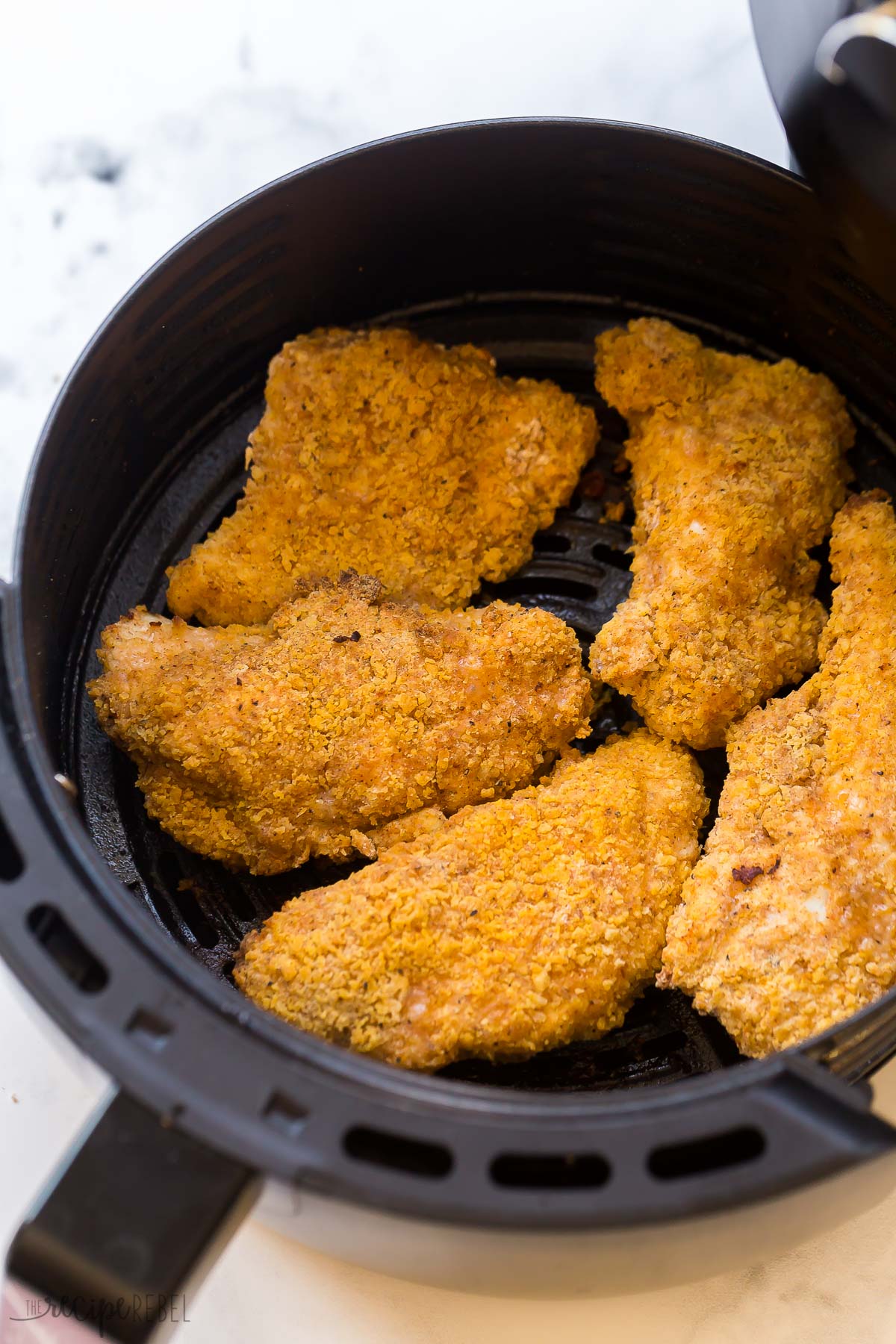 This Air Fryer Fried Chicken is a 20-minute recipe for the best "fried" chicken! It's tender and juicy on the inside with a perfectly golden-brown, crispy, and flavorful exterior. It's a healthier, easier, less-mess alternative to classic fried chicken! #airfryer #chicken #recipes | air fryer recipes | air fryer chicken breast | air fryer chicken recipes | easy dinner ideas | healthy dinner ideas close up image of cooked air fryer fried chicken in air fryer basket