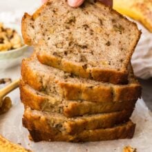 stack of banana nut bread slices with hand grabbing top piece