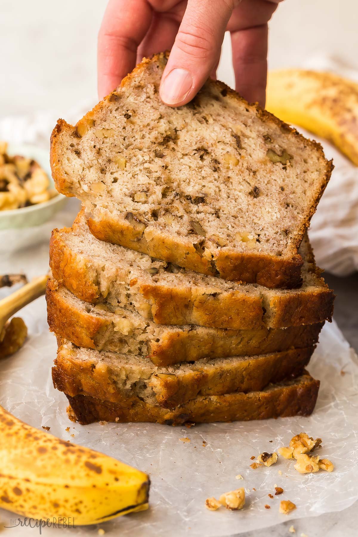 stack of banana nut bread slices with hand grabbing top piece