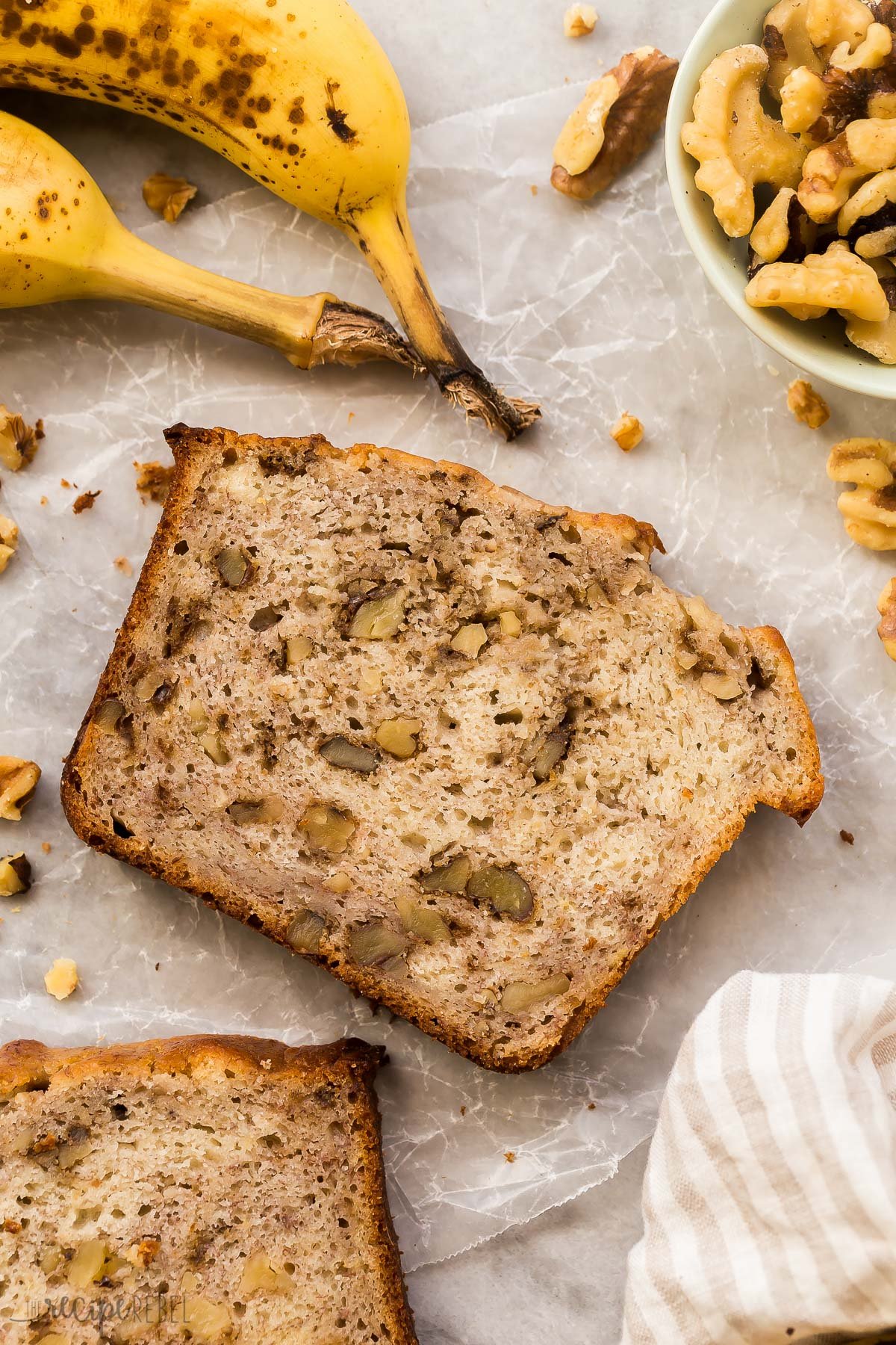 single slice of banana bread with bananas and walnuts around