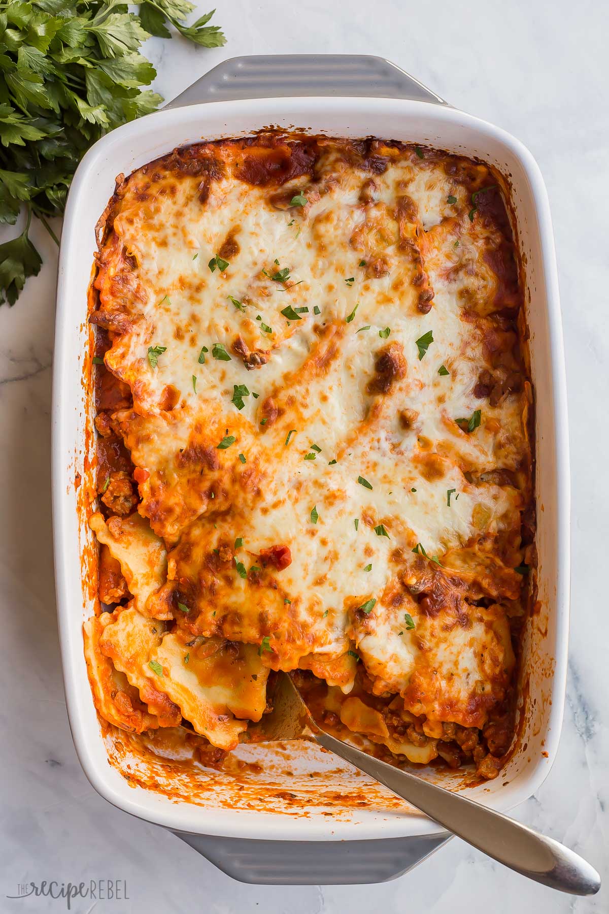 overhead image of pan of baked ravioli with spoon stuck in