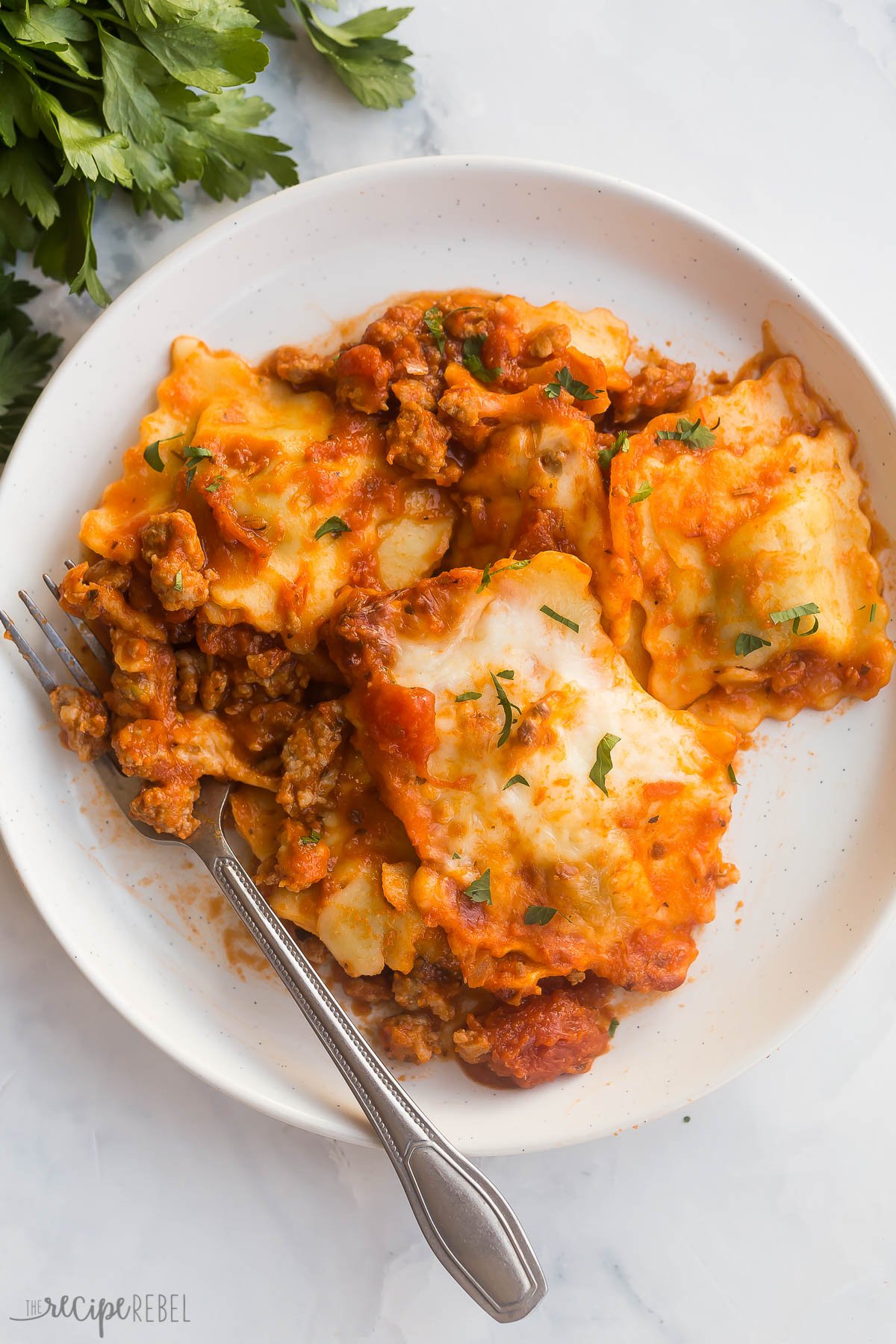 overhead image of baked ravioli on white plate with fork