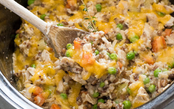 crockpot chicken and wild rice being scooped from slow cooker with spoon