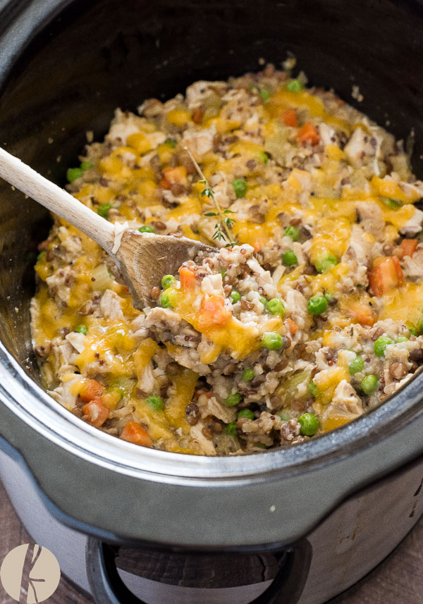 crockpot chicken and wild rice being scooped from slow cooker with spoon