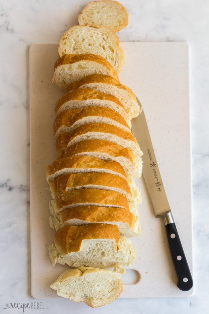 french bread loaf sliced on white cutting board
