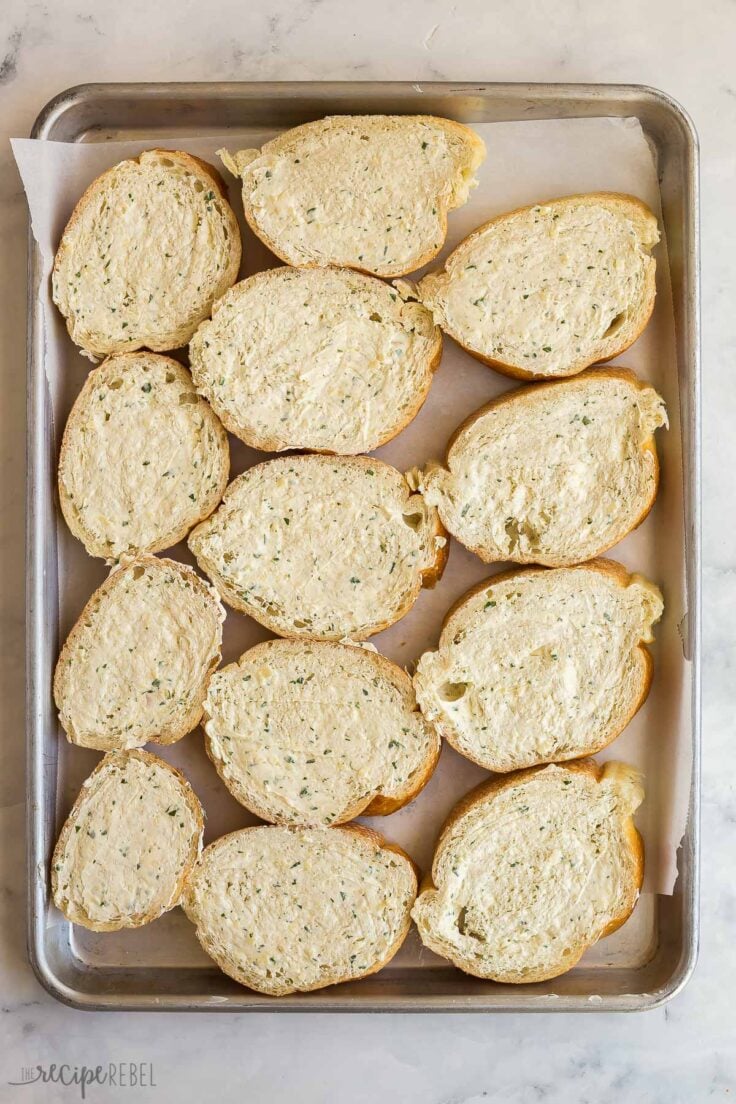 overhead image of bread slices on a pan spread with garlic butter