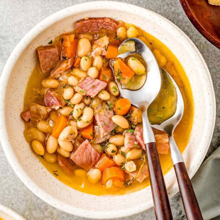 overhead image of bowl of ham and bean soup with two spoons