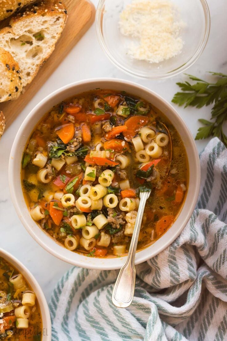 This Italian Sausage Soup is made in just one pot and takes 10 minutes to prep! It's an easy dinner that's loaded with flavorful Italian sausage, tons of veggies, perfectly cooked noodles, and parmesan cheese! #soup #recipe #dinner | easy soup recipes | italian sausage recipes | healthy soup recipes | noodle soup | easy dinner recipes single bowl of italian sausage soup with spoon stuck in