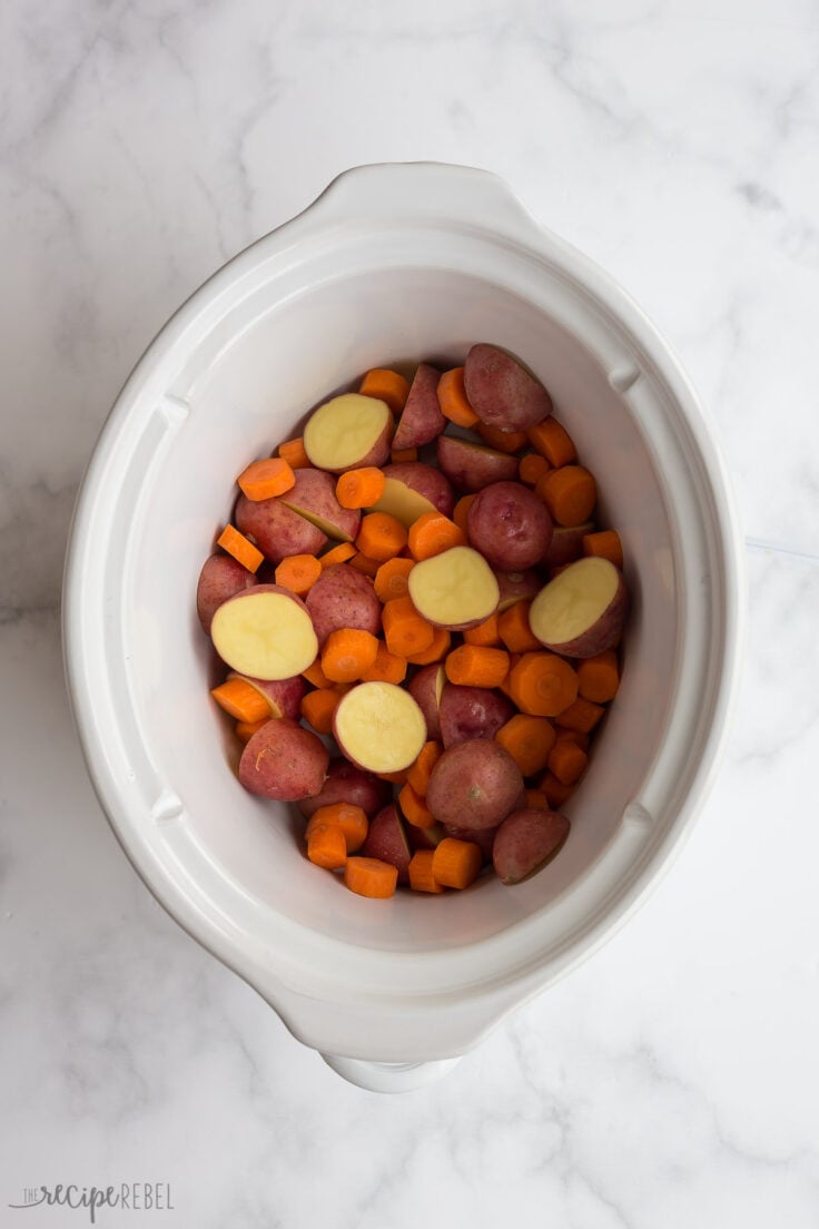 halved potatoes and carrots in white slow cooker