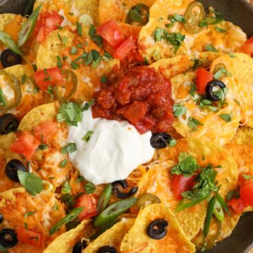 close up image of air fryer nachos with salsa and sour cream