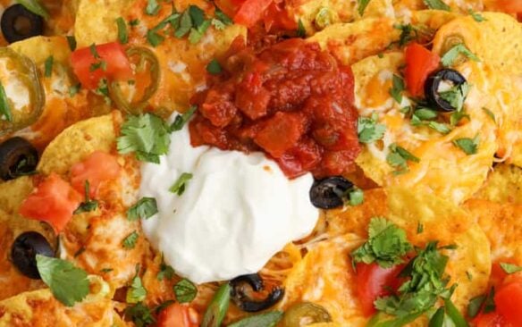 close up image of air fryer nachos with salsa and sour cream
