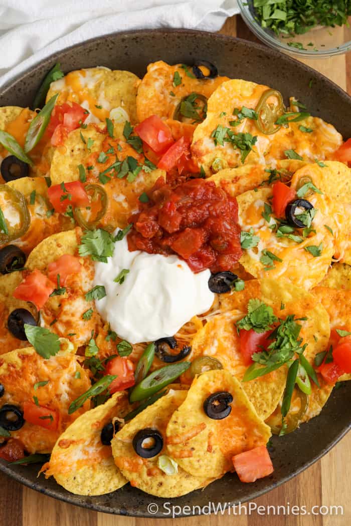 close up image of air fryer nachos with salsa and sour cream