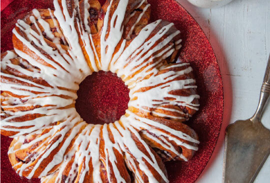 cranberry spiral bread with icing on a red plate