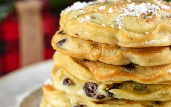 stack of white chocolate cranberry pancakes with christmas decorations in the background