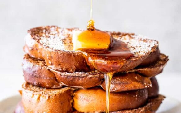 stack of eggnog french toast with butter and syrup