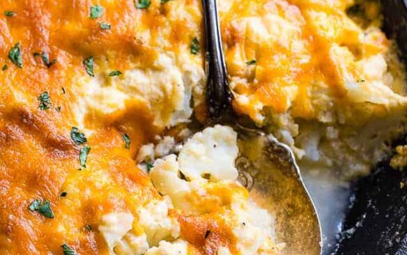 cauliflower au gratin in black skillet with spoon