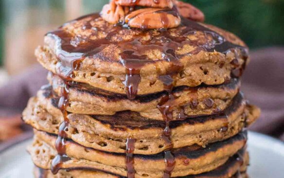 tall stack of gingerbread pancakes with syrup dripping down