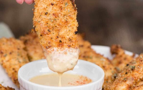 air fryer chicken tenders being dipped into sauce