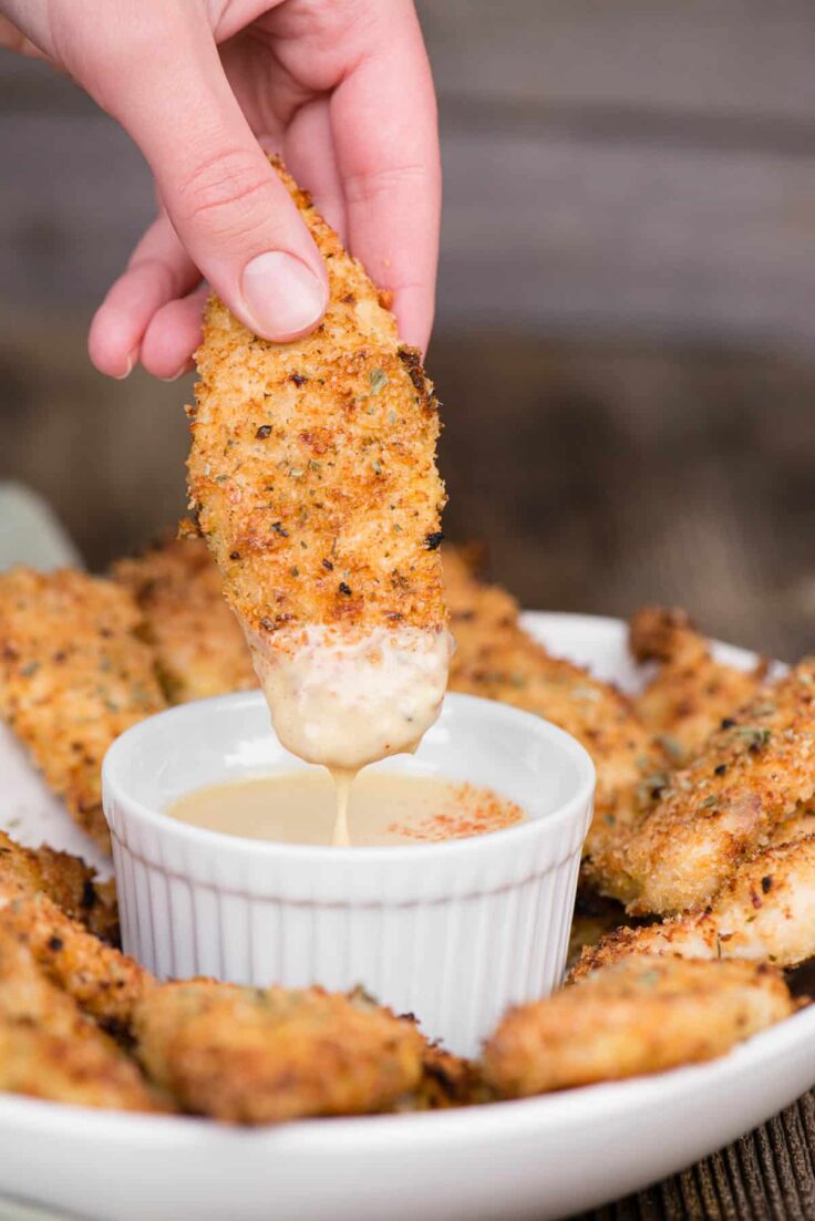 air fryer chicken tenders being dipped into sauce