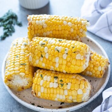corn cobs cut in half stacked on plate