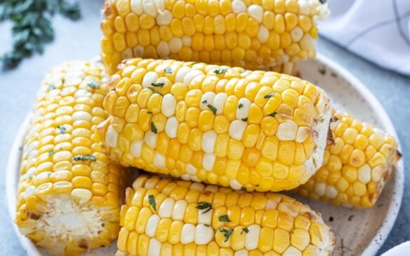 corn cobs cut in half stacked on plate