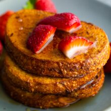 three slices of air fryer french toasted stacked with strawberries on top