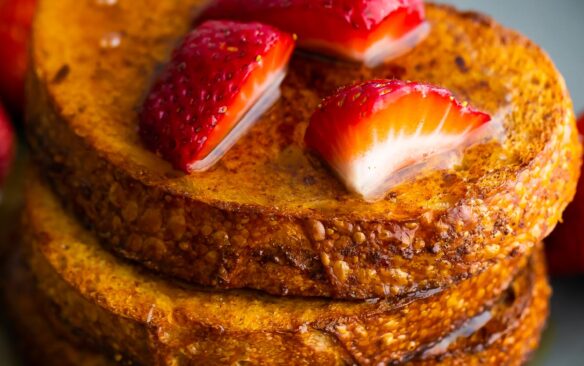 three slices of air fryer french toasted stacked with strawberries on top