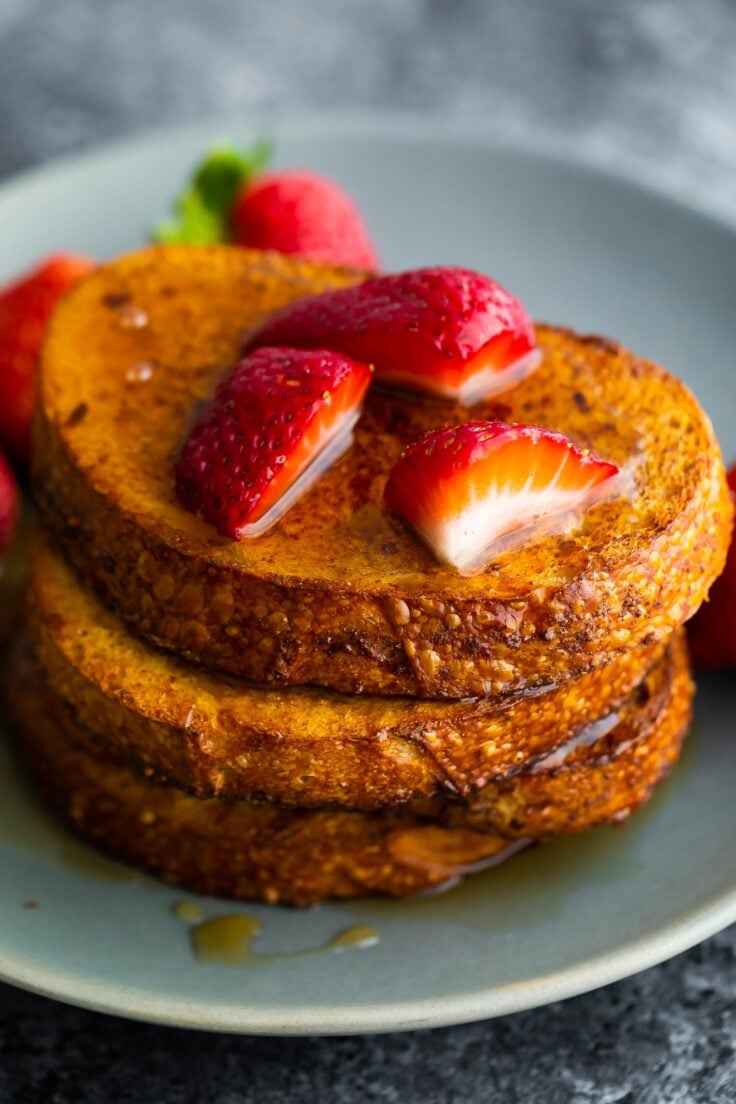 three slices of air fryer french toasted stacked with strawberries on top