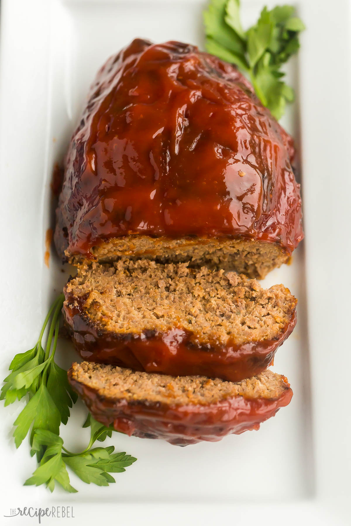 This Air Fryer Meatloaf is classic comfort food made quicker and easier in the air fryer! It's moist, tender, and juicy in the middle, with a slightly crispy exterior. #airfryer #dinner #recipes | air fryer recipes | air fryer dinner | ground beef recipes | easy dinner recipes | air fryer meatloaf on white platter with two slices cut