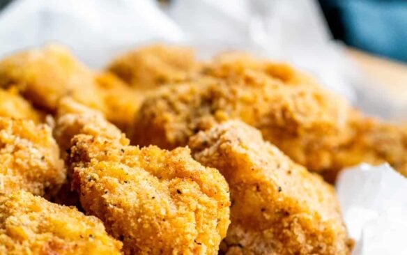 air fryer popcorn chicken in basket with parchment paper