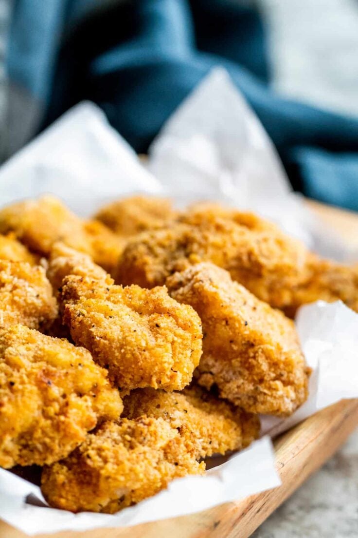 air fryer popcorn chicken in basket with parchment paper