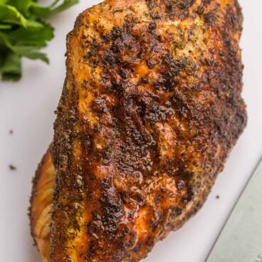 close up pf whole air fryer turkey breast on white cutting board