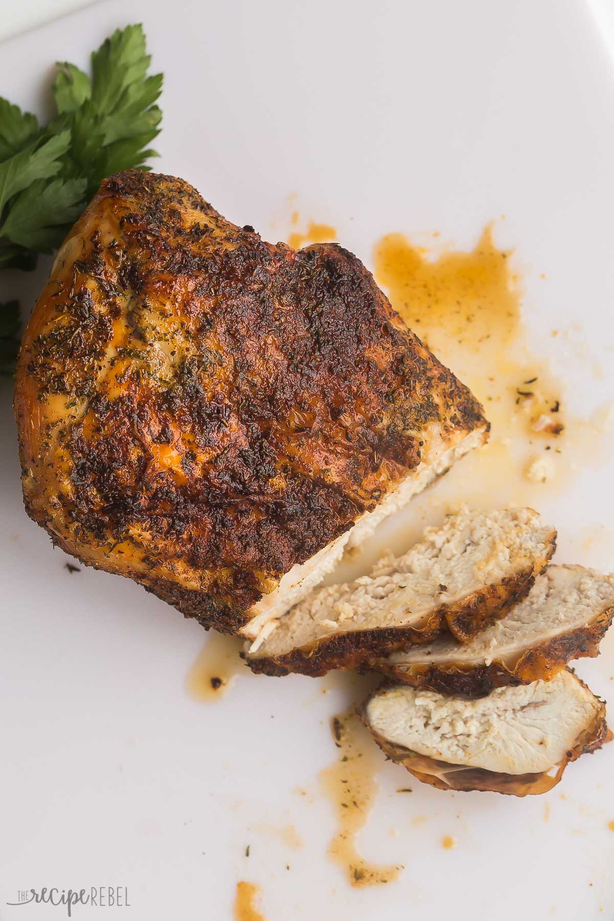 This Air Fryer Turkey Breast is a simple recipe that takes just 5 minutes to prep! Fresh turkey breast is slathered in a simple yet flavorful blend of seasonings, then air fried until fall-apart tender in the middle and golden-brown on the outside! #airfryer #turkey #thanksgiving #recipes | thanksgiving recipes | christmas recipes | turkey recipes | turkey breast | boneless turkey breast | holidays air fryer turkey breast on white cutting board with three slices cut