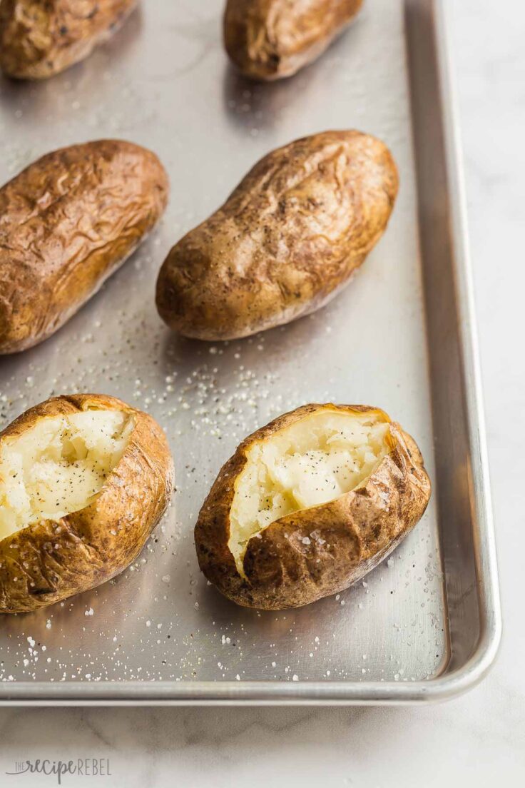 baked potatoes on a baking sheet with two split open