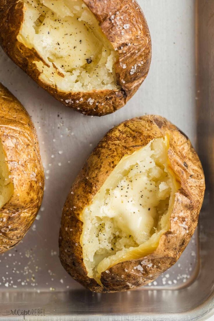 close up overhead image of baked potato split open with butter