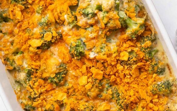 wooden spoon stuck into broccoli casserole with crushed crackers on top.