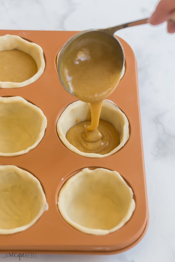 butter tart filling being poured into unbaked pastry shells
